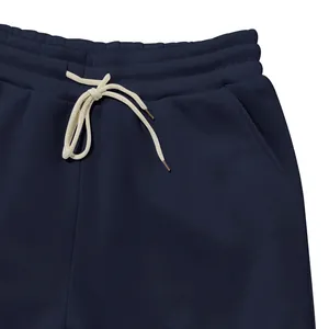 Detailaufnahme einer marineblauen Fleece-Jogginghose mit weißem Kordelzug am Bund.