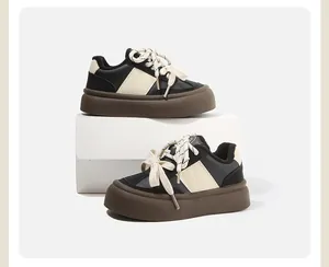 Stijlvolle kinder sneakers met plateauzool in zwart en crème met bruine zool.