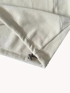 Dettaglio del tessuto in pile polare crema con coulisse regolabile e fermo in metallo.