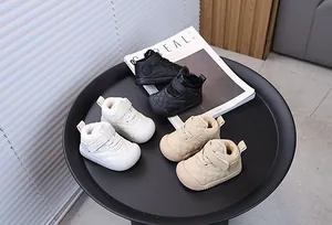 Close-up of three pairs of padded toddler shoes in black, white, and beige on a tray