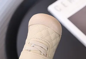Close-up of beige quilted toddler shoes with protective rubber toe cap detail