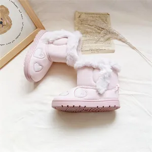 Close-up of pink girl's snow boots featuring white faux fur and embroidered hearts