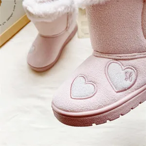 Detailed macro shot of pink children's snow boots featuring heart embroidery and faux fur lining