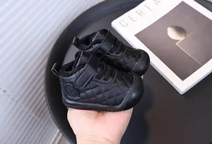 Close-up of black quilted warm baby walking shoes with plush lining being held by hand