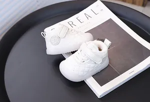 Close-up of white quilted toddler walking shoes with warm fleece lining on a magazine.
