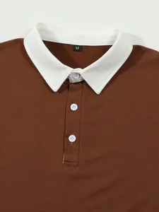 Detail of brown long sleeve Polo shirt with white contrast collar and buttons.