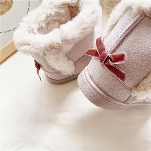 Close-up detail of pink girls snow boots featuring plush fur and a velvet bow decoration