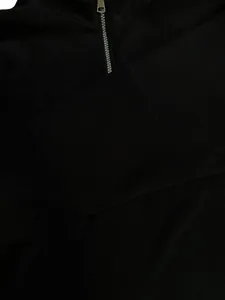 Detailopname van zachte zwarte polarfleece stof en de zilveren metalen kwartrits sluiting.