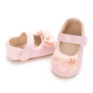 Detail von rosa Baby-Mary-Janes mit großer Schleife und goldenem Verzierungsknopf
