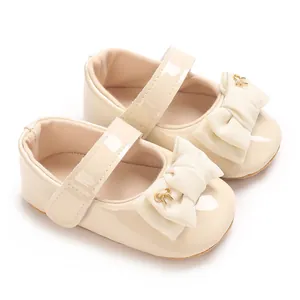 Nahaufnahme von cremefarbenen Baby-Mary-Janes mit großer Schleife und Goldverzierung