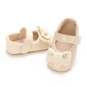 Nahaufnahme von cremefarbenen Baby-Mary-Janes mit Schleife und goldenem Schmetterling