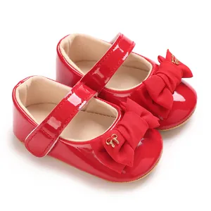Detailaufnahme von roten Baby Mary Jane Schuhen mit Stoffschleifen und goldenen Akzenten.