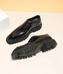 Detail of shiny black leather Oxford brogue shoes with thick lug soles and engraving.
