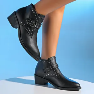 Detailweergave van zwarte Chelsea-laarzen voor dames met zilveren klinknagels en gesp.