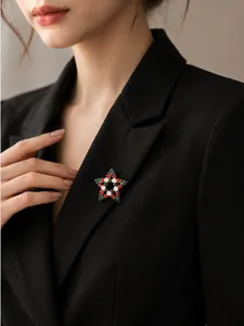 Nahaufnahme der Weihnachts-Sternbrosche mit roten und grünen Strasssteinen auf Blazer