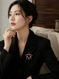 Detailansicht einer bunten Weihnachts-Sternbrosche mit Strass auf einem schwarzen Blazer