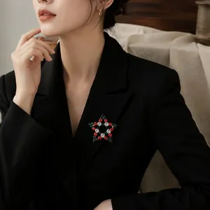 Eleganter Weihnachtsstern-Brosche mit roten und grünen Steinen auf einem Blazer.
