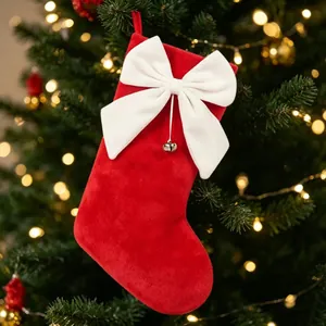 Detailansicht eines roten Plüsch-Weihnachtsstrumpfs mit großer weißer Schleife und Glocke