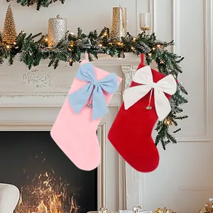 Plüschige Weihnachtssocken mit großen Schleifen und Glocken an einem festlichen Kamin