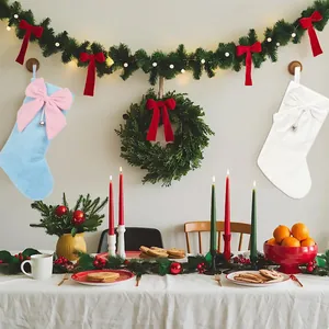 Zwei Plüsch-Weihnachtssocken mit großer Schleife und Glocke in festlicher Raumszene