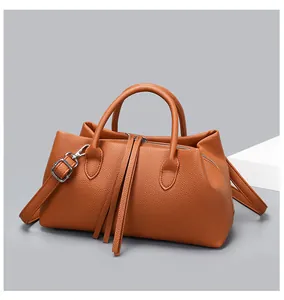 Close-up detail of a brown pebble grain leather tote bag with stylish long tassels