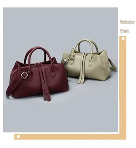 Detail of two vintage leather tote bags in burgundy and beige with tassels.
