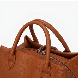 Detail view of brown pebbled leather tote bag featuring sturdy handles and silver zipper