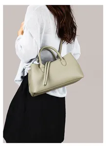 Detail view of a sage green pebbled leather tote bag worn as a stylish shoulder bag.