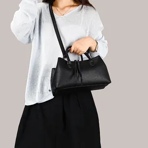 Minimalist black pebbled leather tote bag with long shoulder strap for women