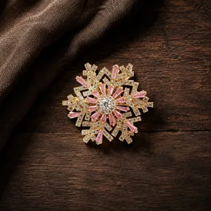 Detailed close-up view of a luxury gold snowflake brooch featuring pink and white crystals