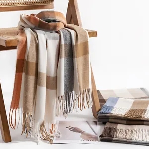 Cozy plaid cashmere-like scarf shawl draped over a wooden chair for autumn and winter.