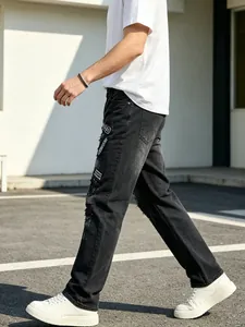 Side profile view of men's black ripped jeans with high-street embroidery patches.