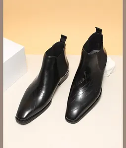 Détail de bottines Chelsea en cuir noir avec motif gravé au laser et bout carré élégant.