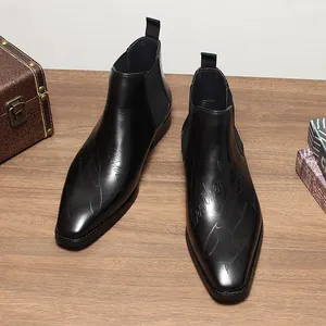 Détail de bottines Chelsea pour hommes en cuir noir avec bout carré et gravure