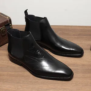 Vue rapprochée de bottines Chelsea en cuir noir à bout carré avec texte stylé gravé au laser.