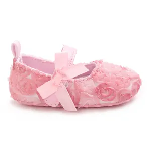 Detailed close-up of pink baby Mary Jane shoes featuring 3D fabric roses and a satin bow