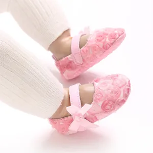 Close-up view of cute pink baby Mary Jane shoes featuring floral lace and bow details