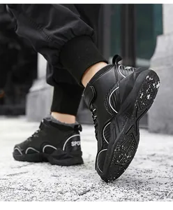 Detail view of boys black winter padded high-top sneakers in outdoor street setting