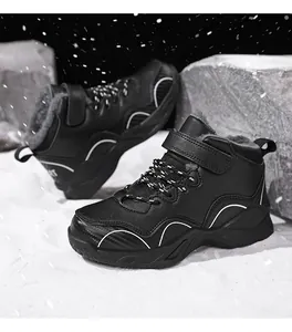 Detailed view of black fur-lined boys winter outdoor sneakers set on a snowy background.