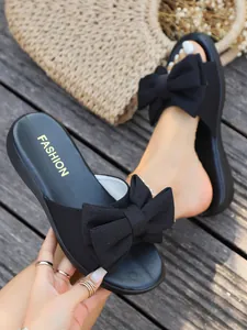 Schwarze flache Damen-Sandalen mit großer Schleife, Sommer-Strandstil auf Holzdeck