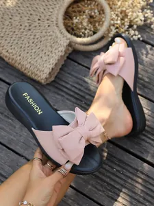 Detailansicht der stylischen rosa Schleifen-Hausschuhe für Damen auf Holzterrasse