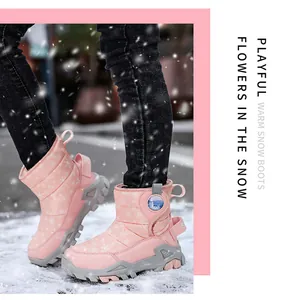 Stivali da neve rosa per bambini con motivi a fiocco di neve indossati sulla neve.