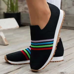 Close-up of women's black fly-knit slip-on sneakers featuring vibrant rainbow stripes design