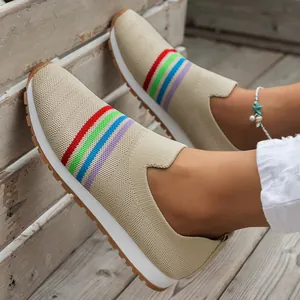 Detailed view of beige flyknit slip-on sneakers with colorful rainbow stripes on feet