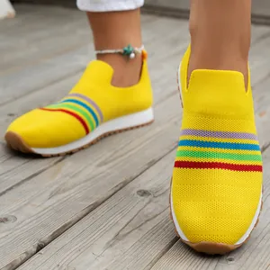 Bright yellow fly-knit slip-on sneakers for women with colorful rainbow stripe details.