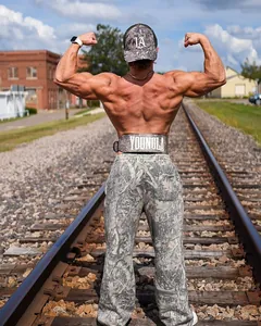 Detaillierte Rückansicht eines Fitness-Models in Camouflage-Hose auf Bahngleisen