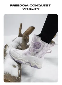 Dettaglio stivali da neve viola per bambini con stampa galassia su un tronco innevato