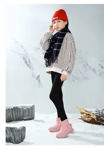 Jeune fille portant des bottes de neige roses à motifs de flocons en décor hivernal