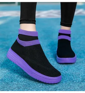 Nahaufnahme von schwarz-violetten Fly-Knit-Sneakern auf einer Laufbahn im Freien.