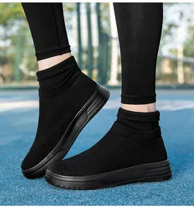 Detailansicht der atmungsaktiven schwarzen Strick-Sneaker auf blauem Sportplatz
